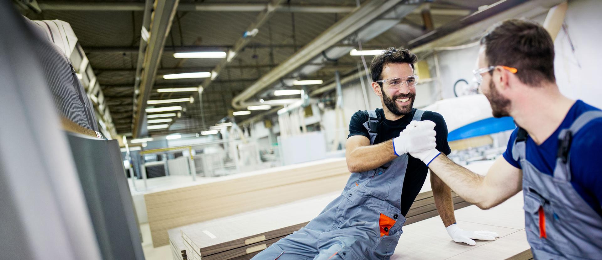Zwei Handwerker geben sich in der Werkstatt die Hand
